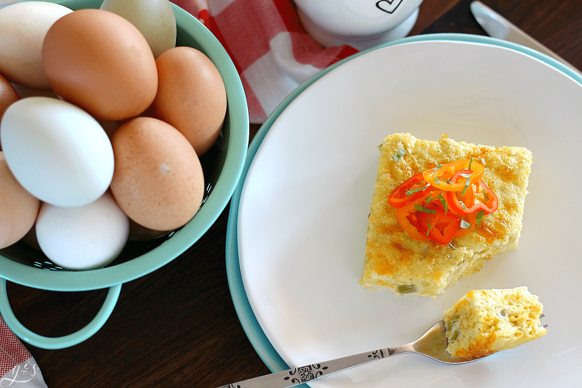 Overhead shot of Southwest Egg Bake on a white plate with farm fresh eggs sitting near. 