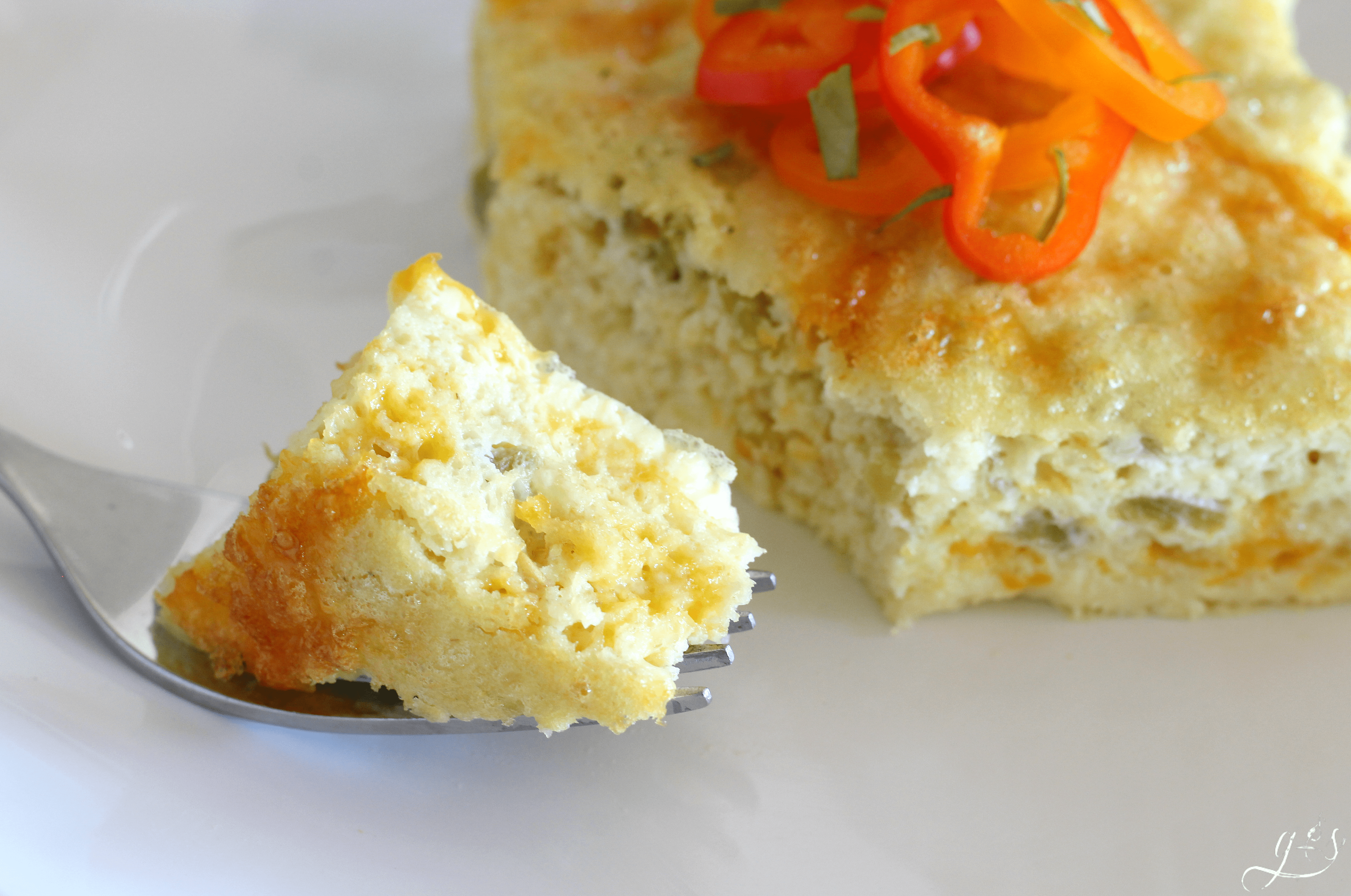 A close up shot of a bite of spicy Egg casserole on a white plate. 