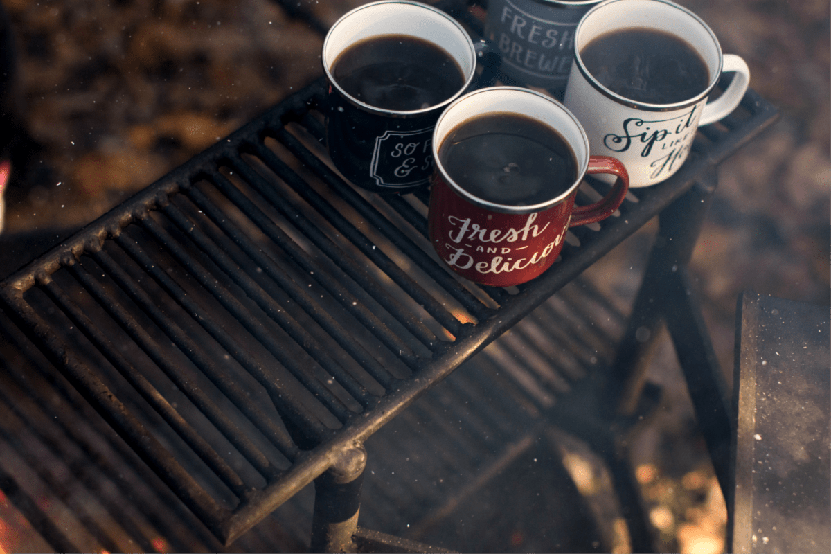 Coffee in mugs outside over a campfire. Fall Bucket List for Foodies