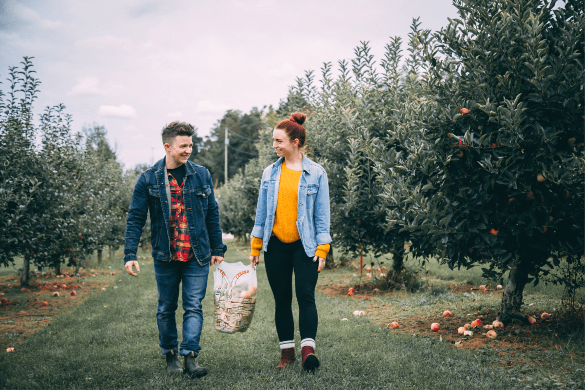 A couple walking in an apple orchard.