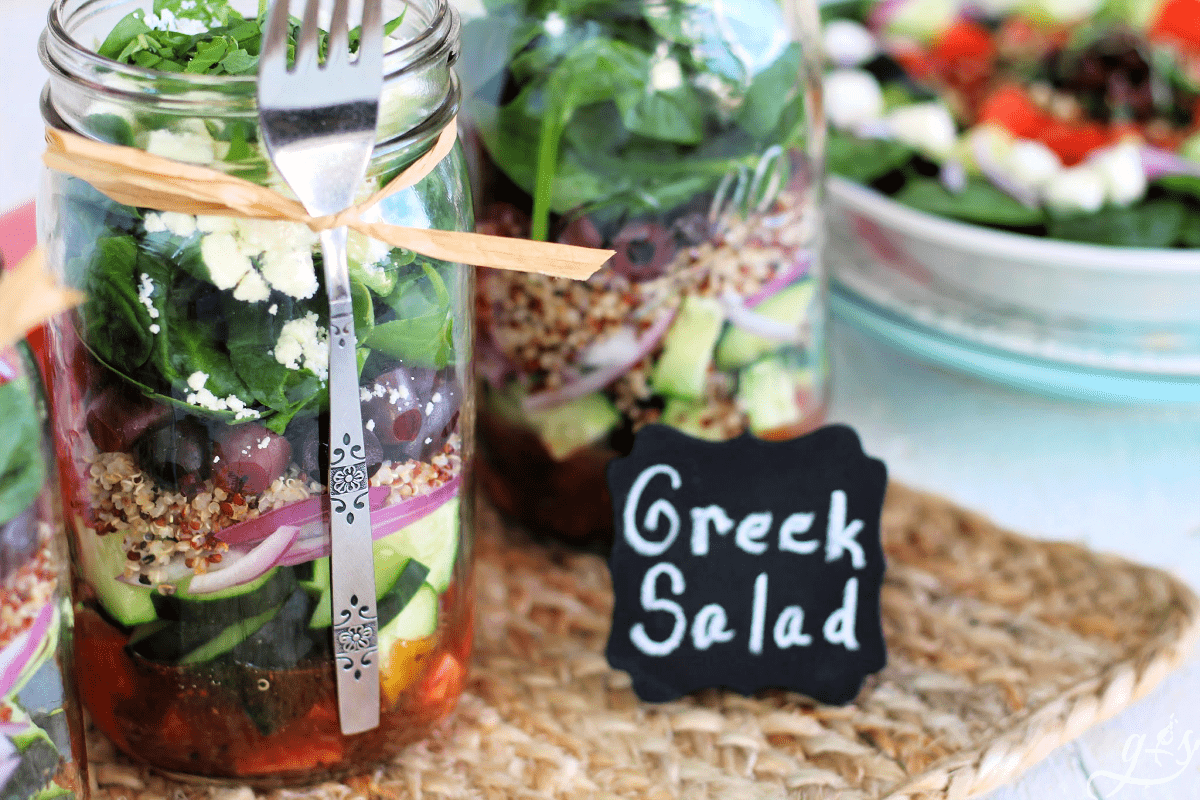 Close up shot of two mason jars filled with clean eating ingredients like Greek Salad. 