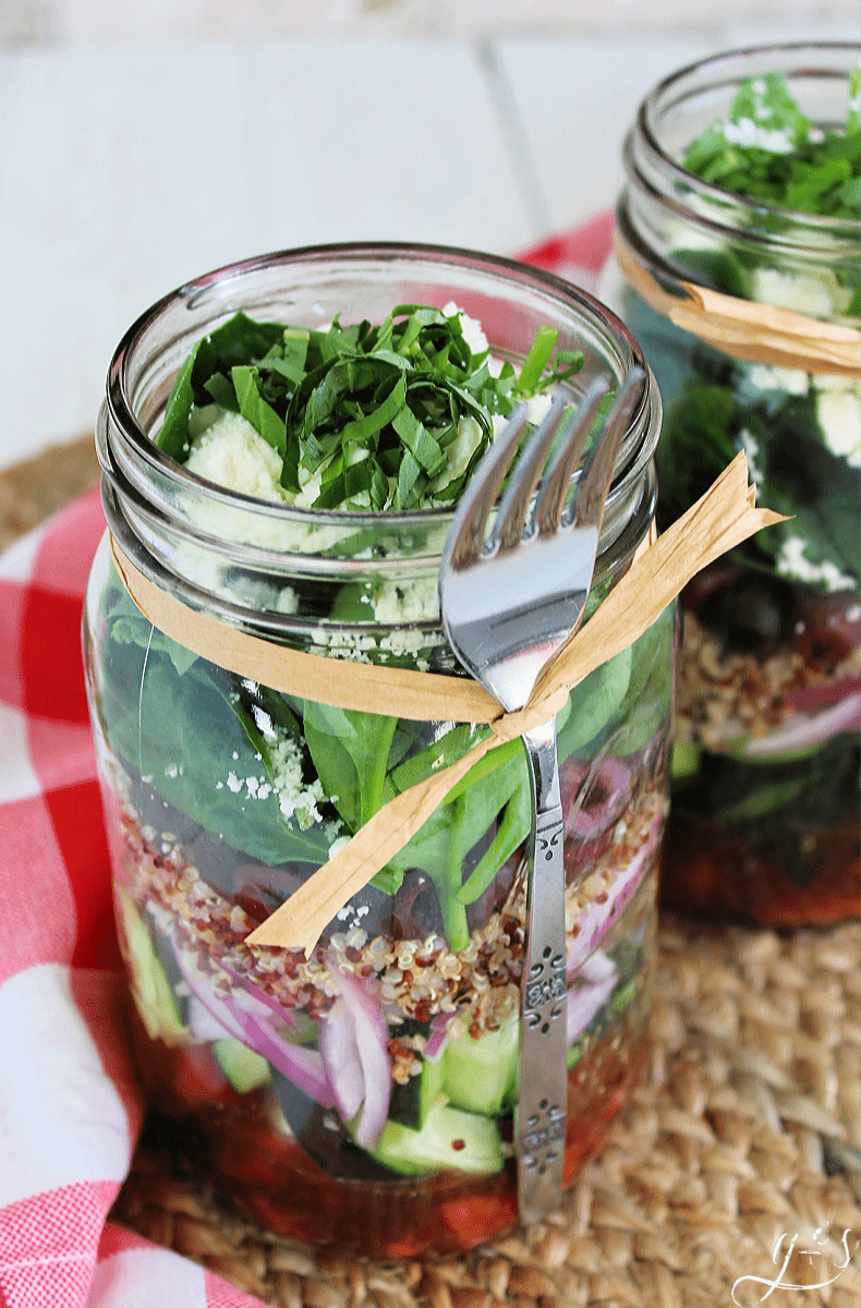 45 degree angle photo of Greek mason jar salads topped with julienned basil.