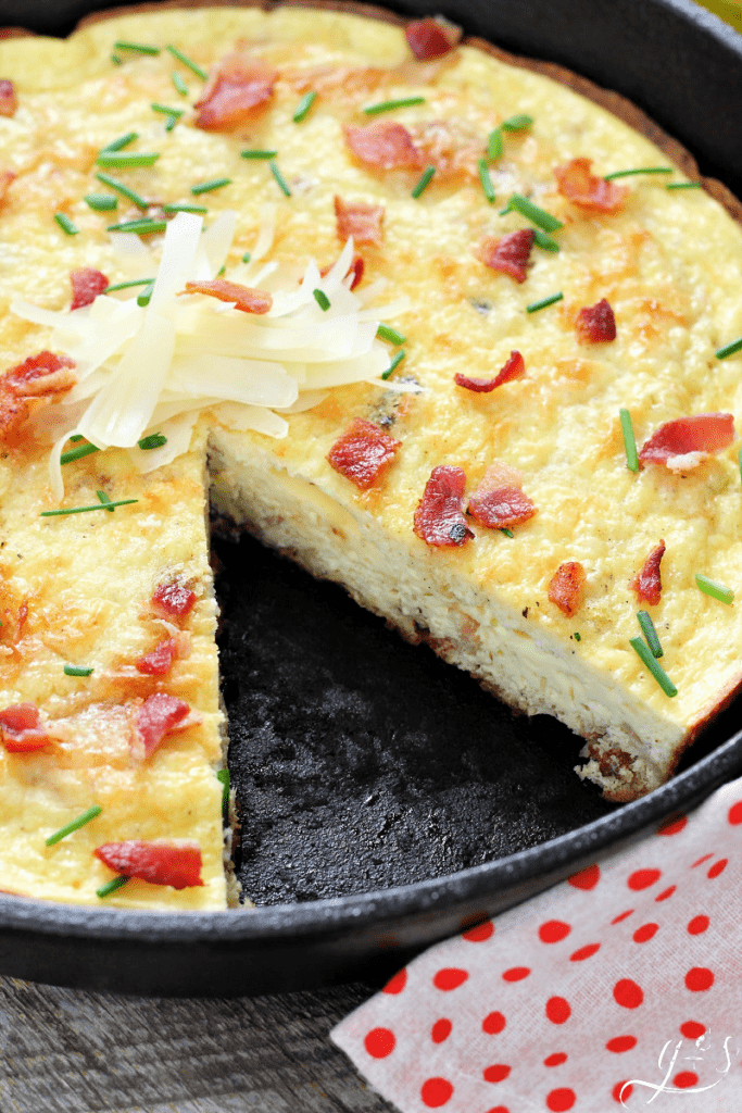 A cast iron pan of frittata with a slice removed.