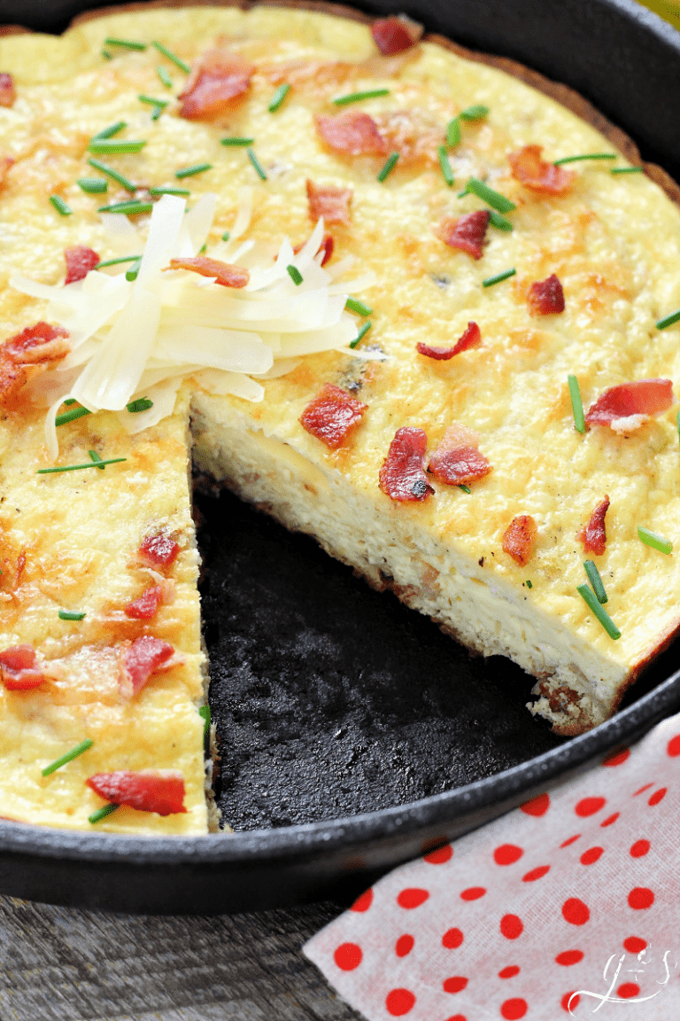 A cast iron pan of frittata with a slice removed.