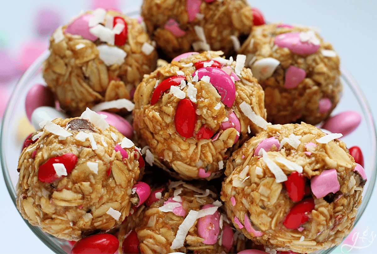 Up close shot of cute energy balls in a clear martini glass using crushed red, white, and pink M&Ms.