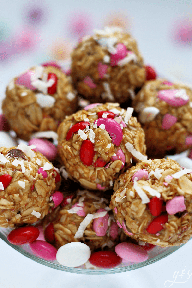 Valentine M&Ms in no bake energy bites in a glass bowl topped with shredded coconut.