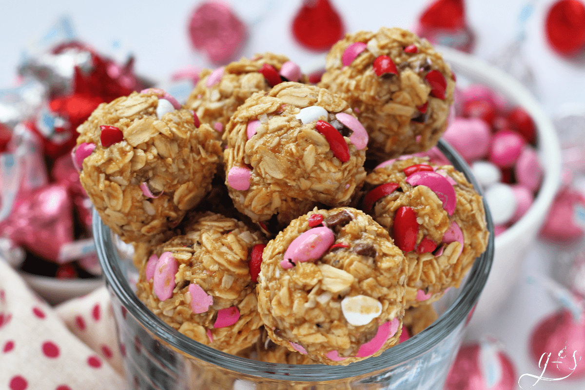 No bake Valentine energy balls with pink, red, and white M&Ms in a glass bowl.