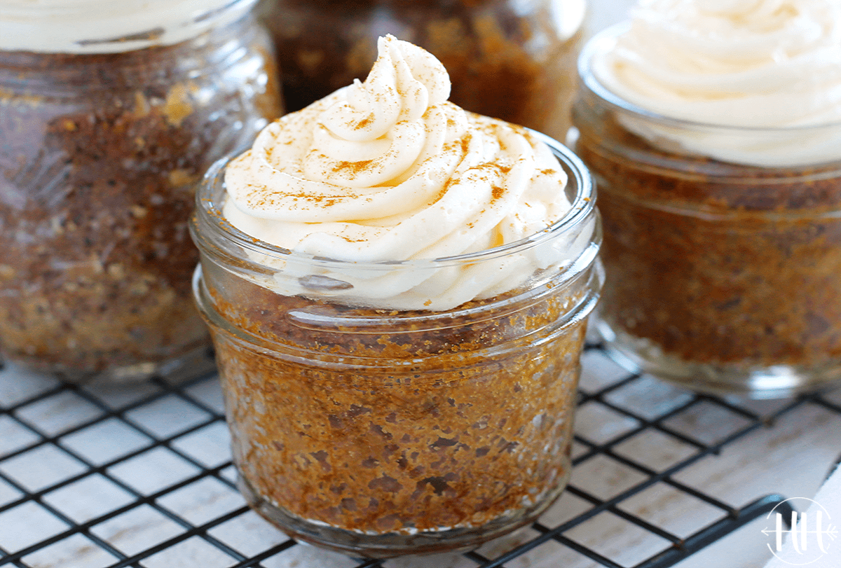 Up close photo of frosted gluten free carrot cake jars on a cooling rack.
