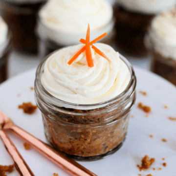 A photo of a pretty mason jar filled with carrot cake and topped with frosting.