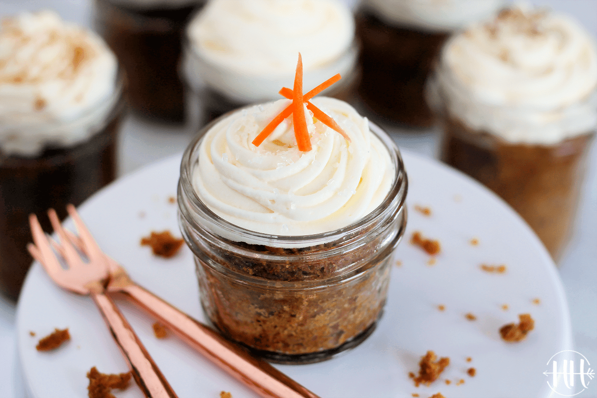 Small mason jar with gluten free carrot cake topped with cream cheese frosting.