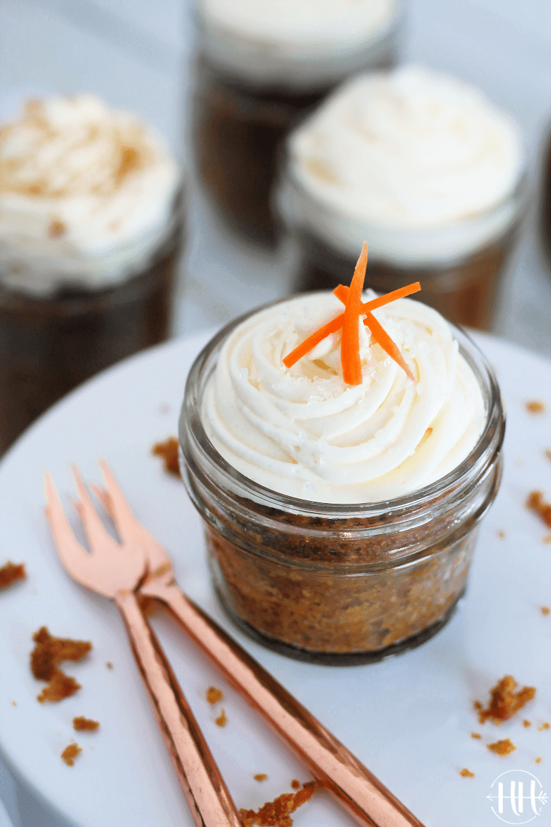 A gluten free carrot cake jar topped with cream cheese frosting and carrot shreds.