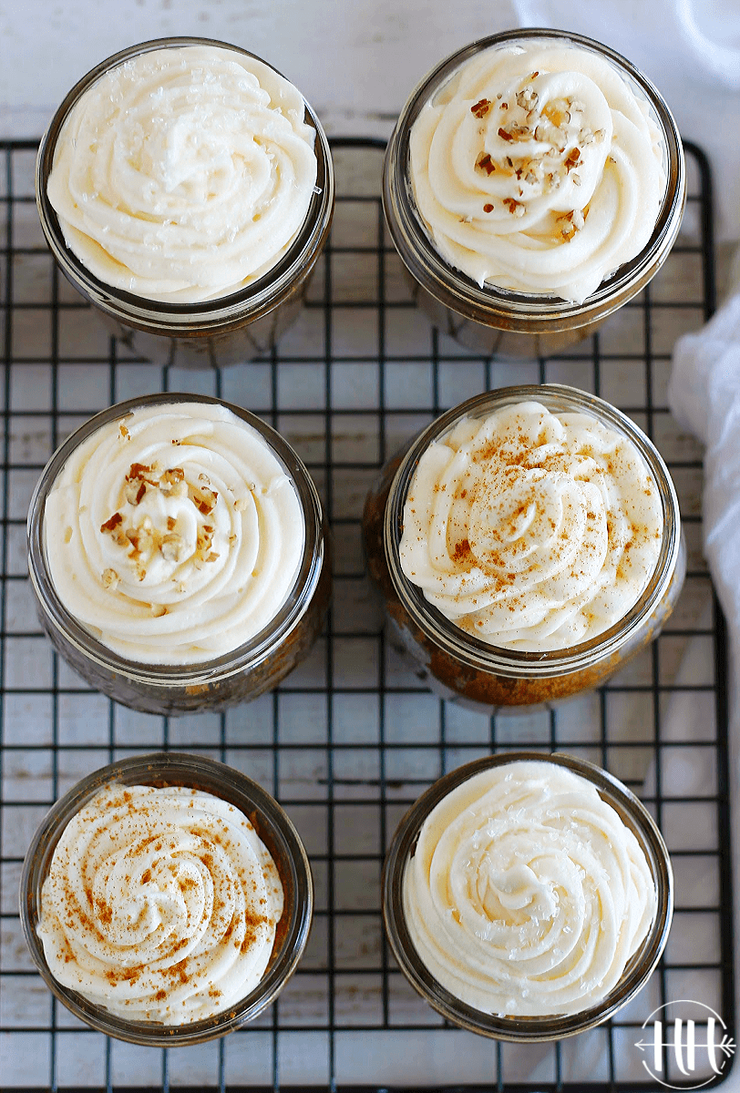 Overhead photo of six carrot cake jars topped with swirled cream cheese frosting.