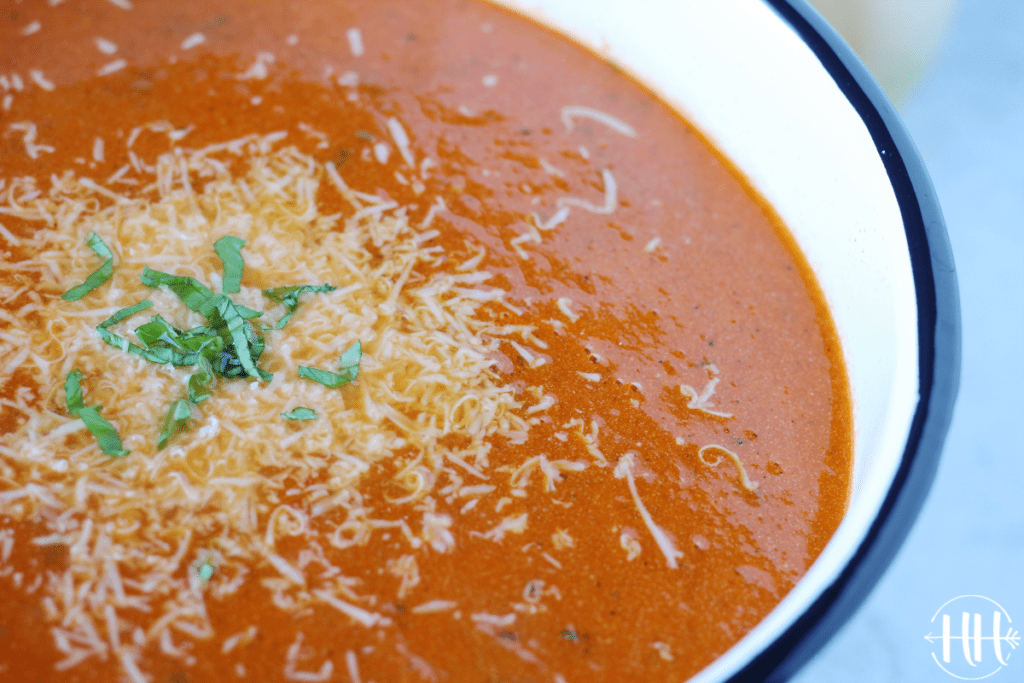 Bowl of creamy tomato basil soup topped with Parmesan cheese.