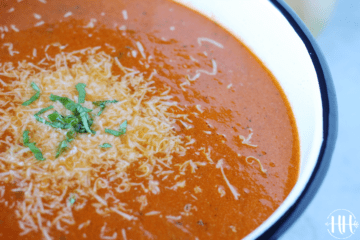 Bowl of tomato soup topped with Parmesan cheese.