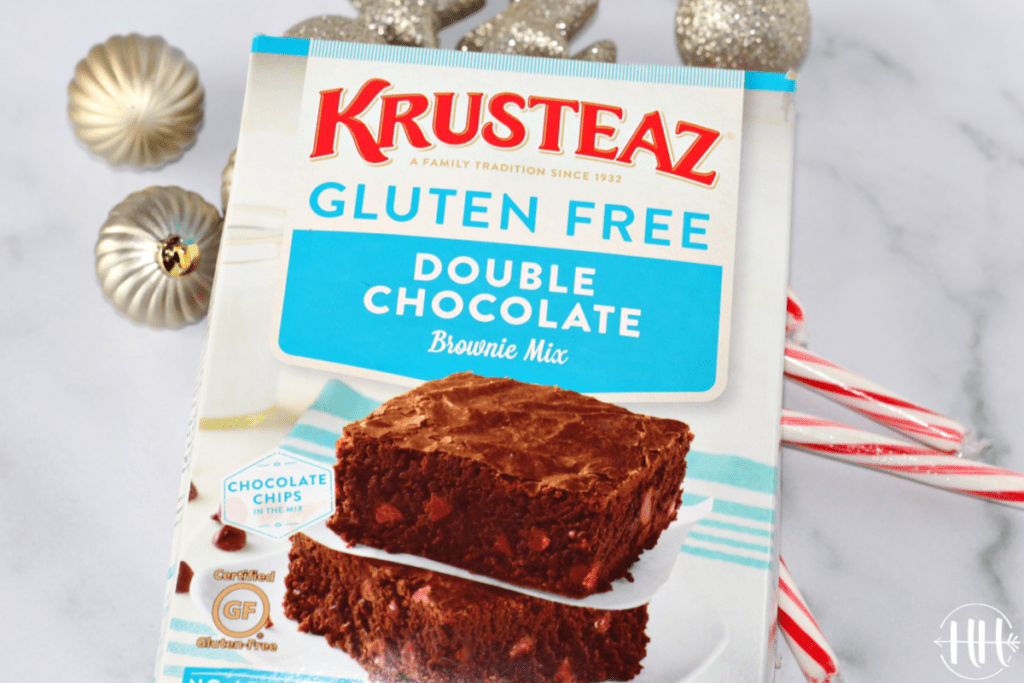 A box of Krusteaz Gluten Free Double Chocolate Brownie Mix on top of candy canes and silver Christmas tree decorations.