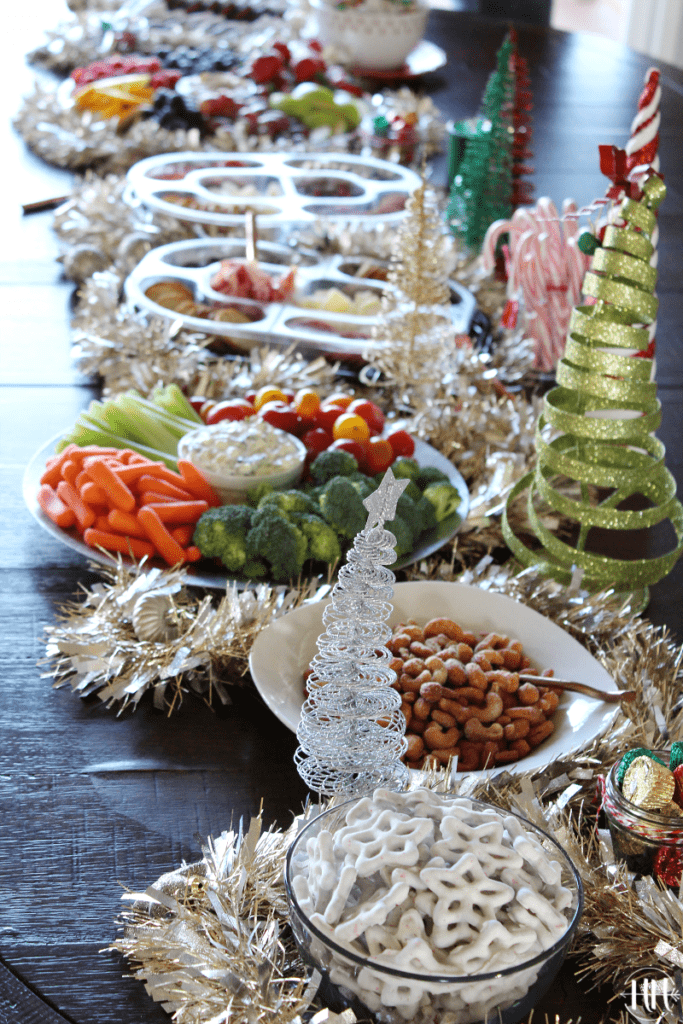 Holiday grazing table with white chocolate covered star pretzels, candied nuts, and vegetables.