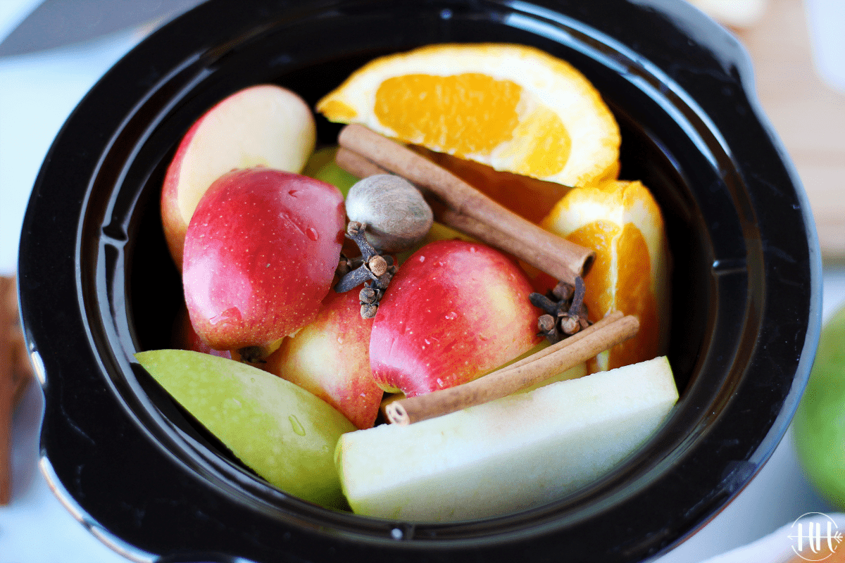 Close shot of colorful apples and orange wedges in a black small cooker insert make for the perfect clean eating fall recipes.
