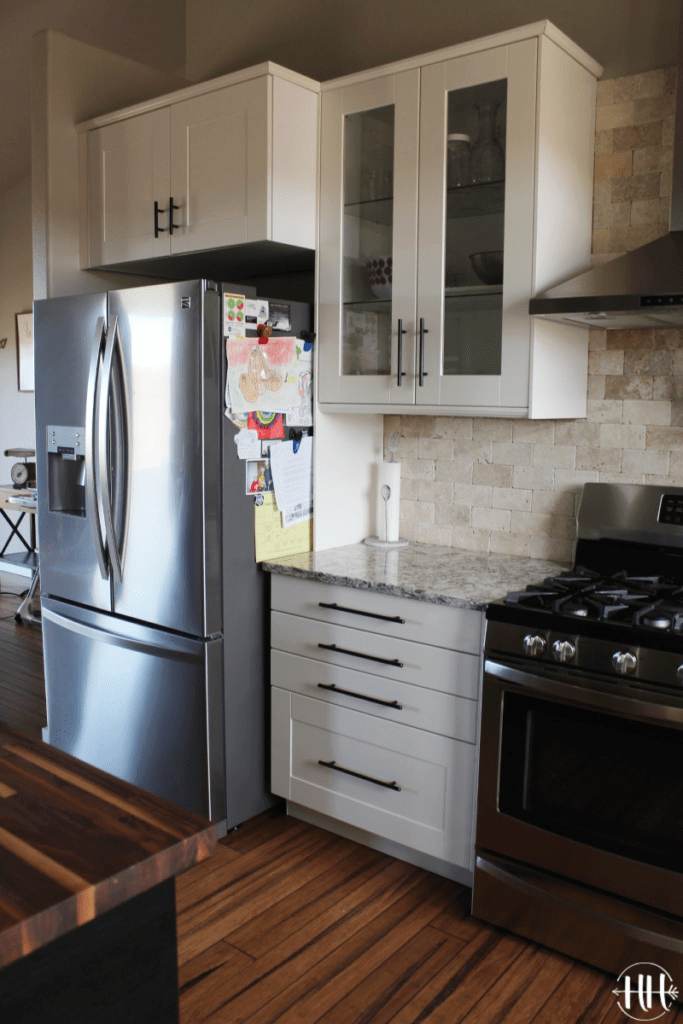 Stainless steel fridge and stove with white IKEA cabinets and Lumber Liquidators Antique Strand bamboo flooring. 