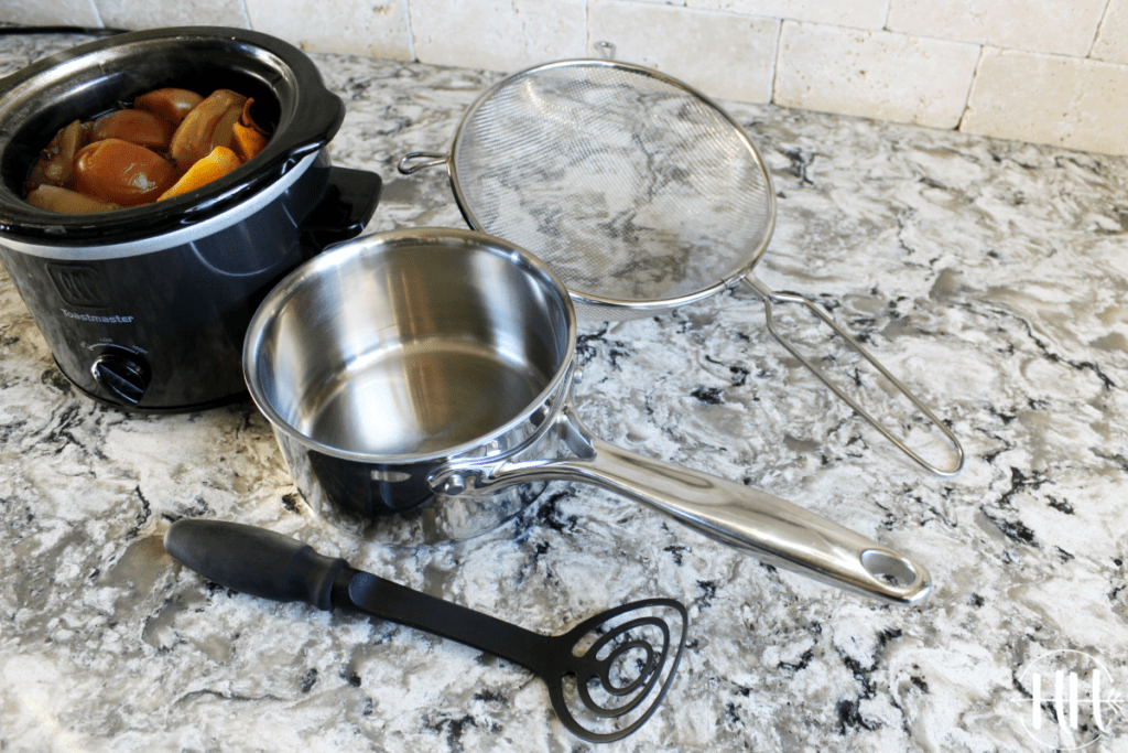 Small soup pot, metal strainer, and avocado masher on countertop.