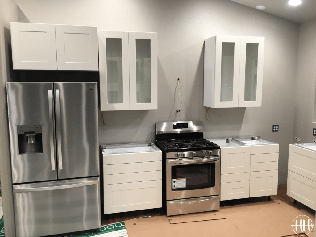 White Sektion IKEA cabinets with glass doors and stainless steel appliances.