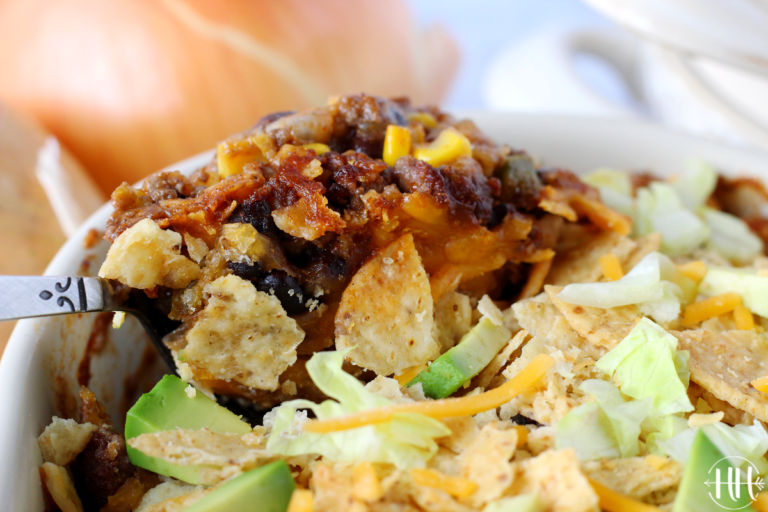 Up close photo of ground beef enchilada casserole being scooped out with a spoon.