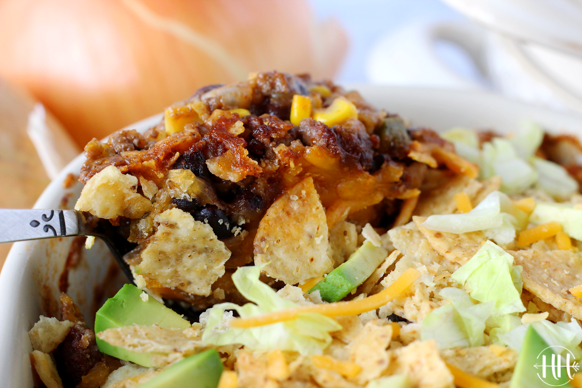 A scoop of Beef Enchilada Casserole topped with crushed tortilla chips and avocado. This is part of whole food family recipes at HappiHomemade.com