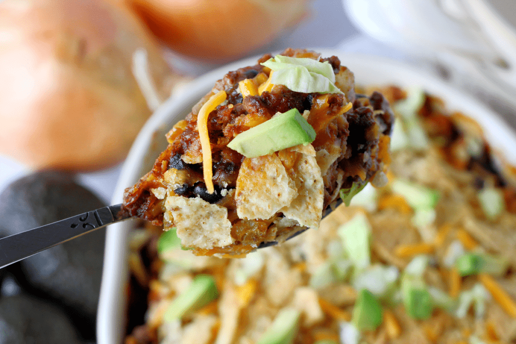 Up close photograph of an enchilada bake on a silver spoon.