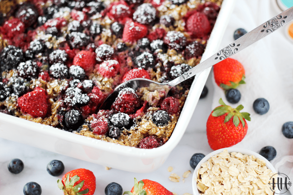 Gorgeous white dish of baked oatmeal with a spoon ready to serve. 