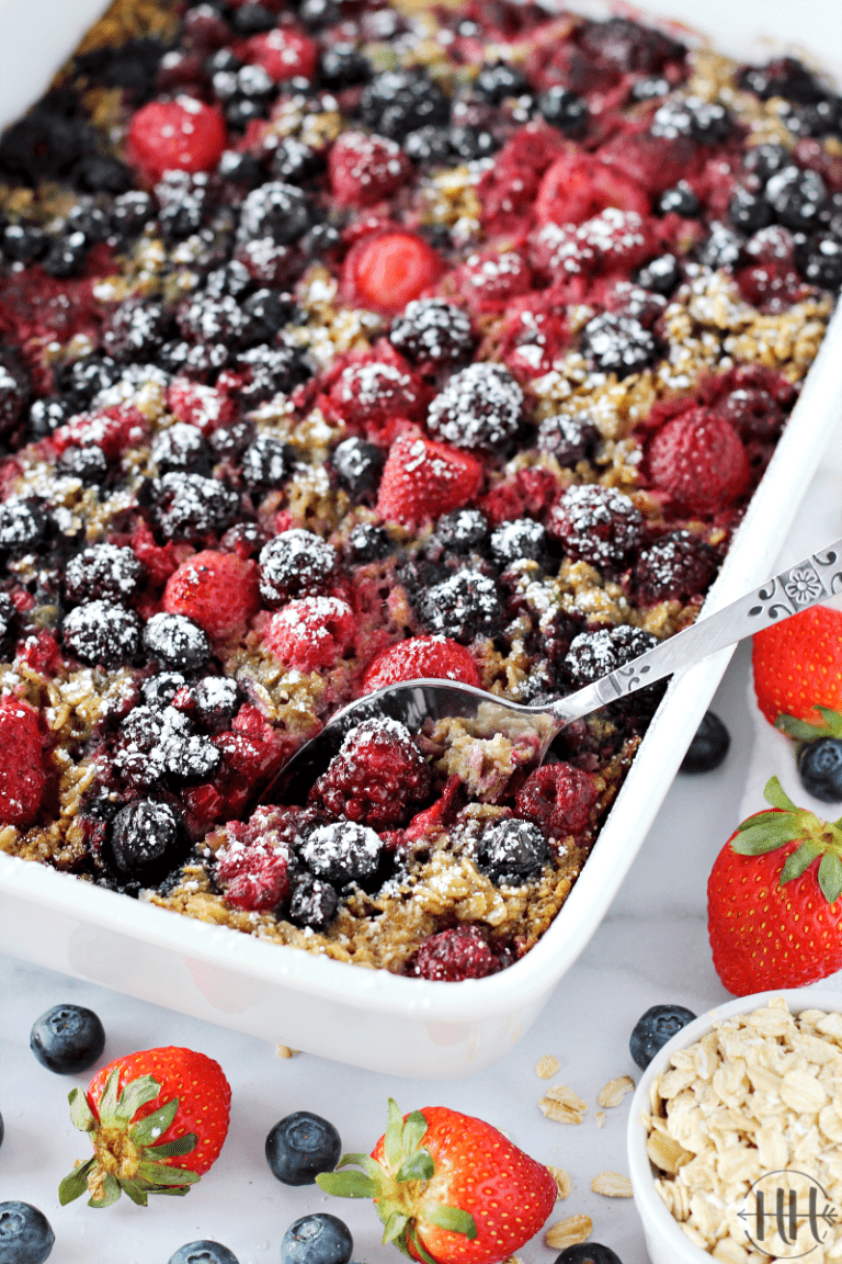 A white dish filled with mixed berry oatmeal bake topped with powdered sugar.