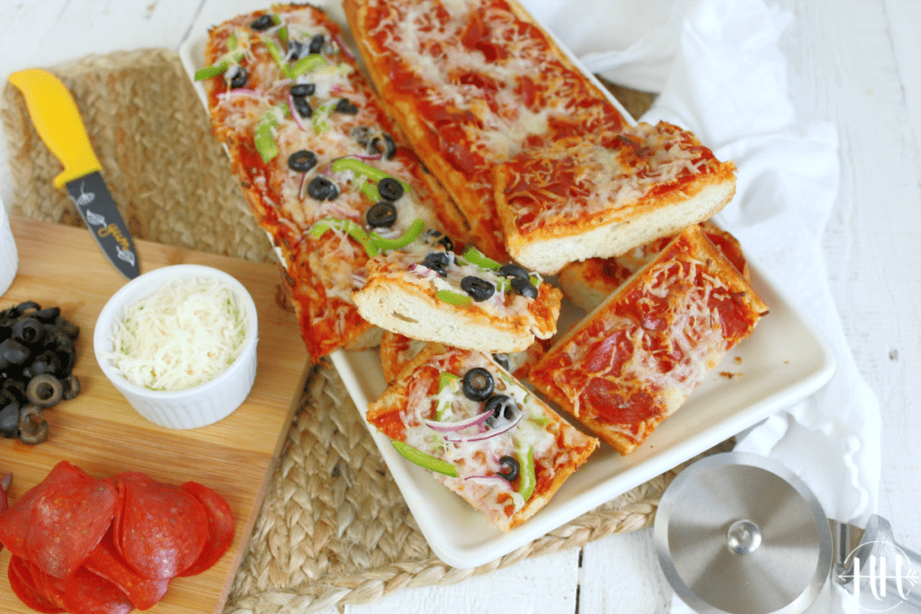 Birds eye view of two halves of a loaf of French bread topped with pizza ingredients. 