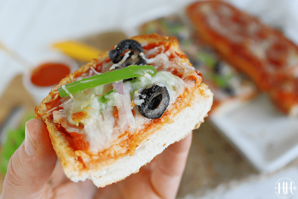 Up close shot of a slice of pizza with green pepper, olives, and onion. 