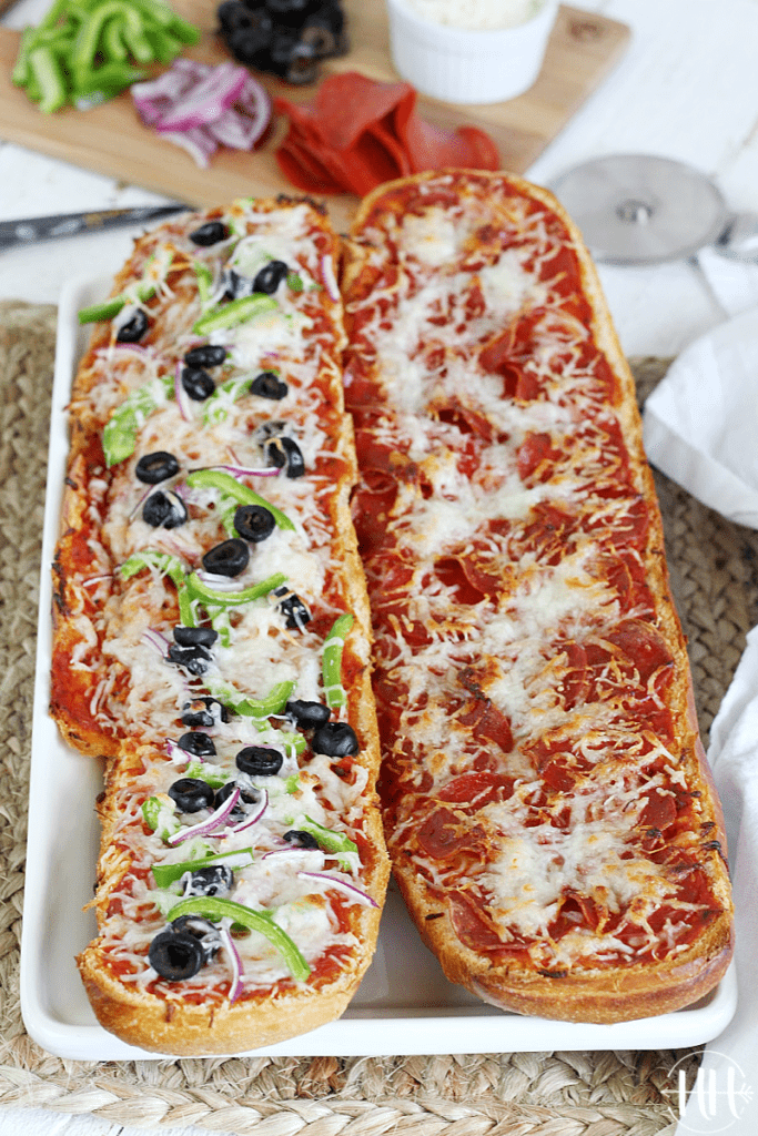 Two halves of an Italian bread loaf used as pizza crust. 