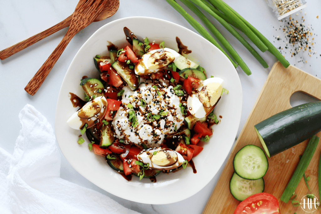 Overhead photo of a white bowl filled with diced cucumber and tomato salad.