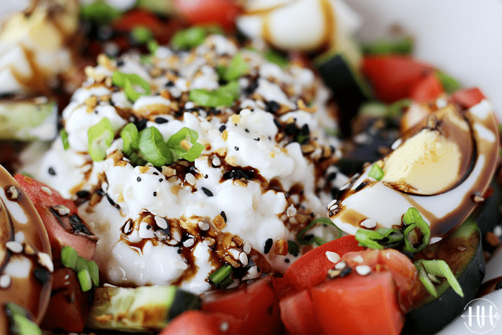 Up close shot of cottage cheese and hard boiled eggs in a bowl with seasoning.