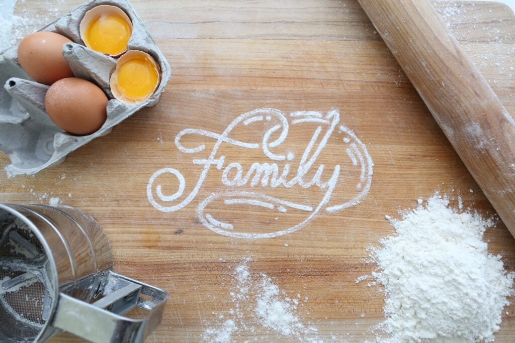 A butcher block countertop with family written in flour. Possibly a play cafe.