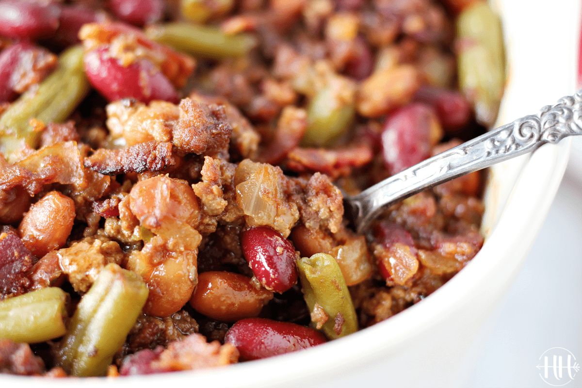 Up close photo of a spoon digging into a pan of calico beans.