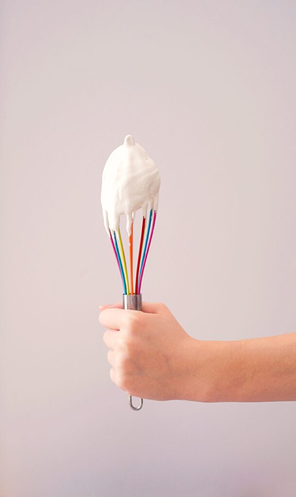 Colorful whisk with white frosting.