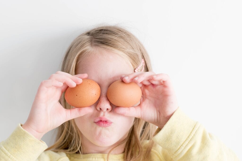 Girl holding eggs to her eyes being silly. 