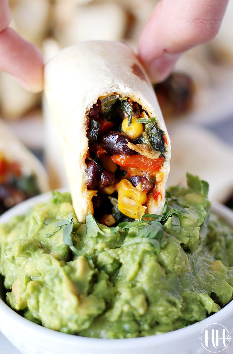 A southwest egg roll being dipped in guacamole.