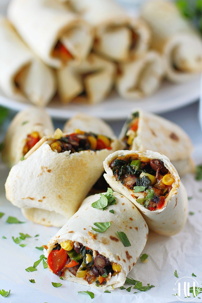 Southwest egg rolls stacked and some cut in half and topped with chopped cilantro.