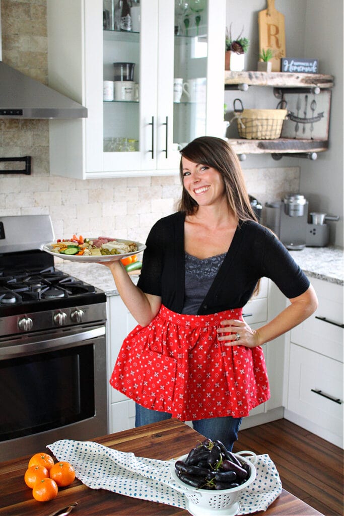 Sammi Ricke of HappiHomemade.com in her kitchen holding a charcuterie board.