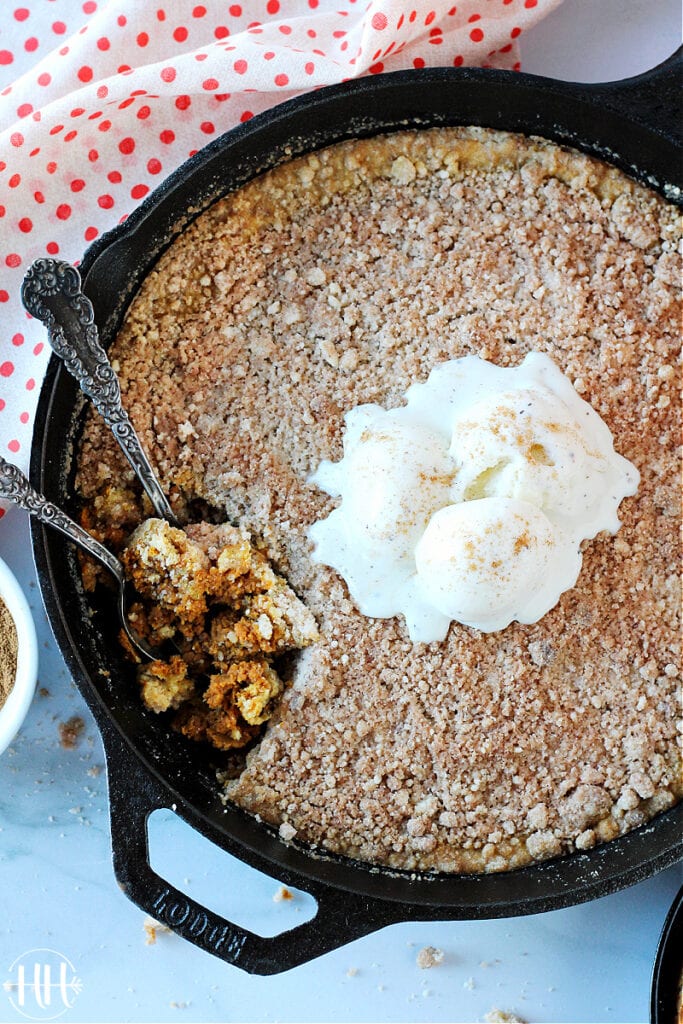 A bird's eye view of a large pan of dairy free pumpkin crisp topped with vanilla bean ice cream. 