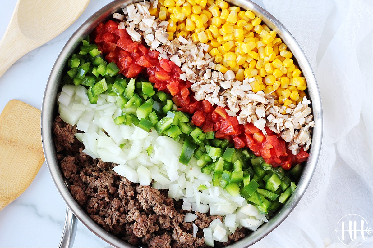 Overhead photo browned ground meat and vegetables grouped in a pan.