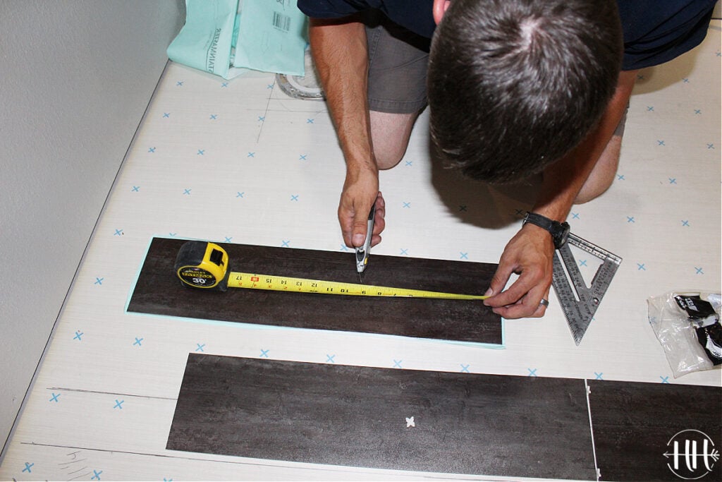 Measuring and cutting a piece of luxury vinyl tile. 