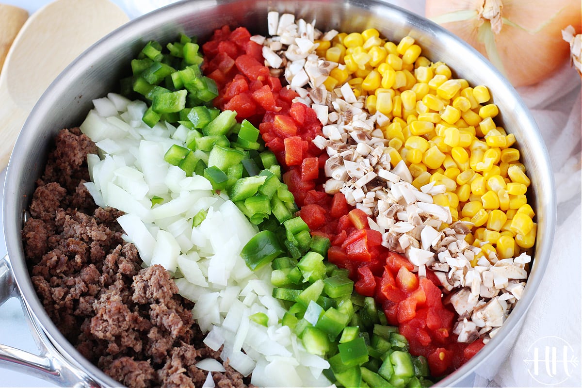 Ingredients for American goulash grouped in a stainless steel pan ready to be mixed.