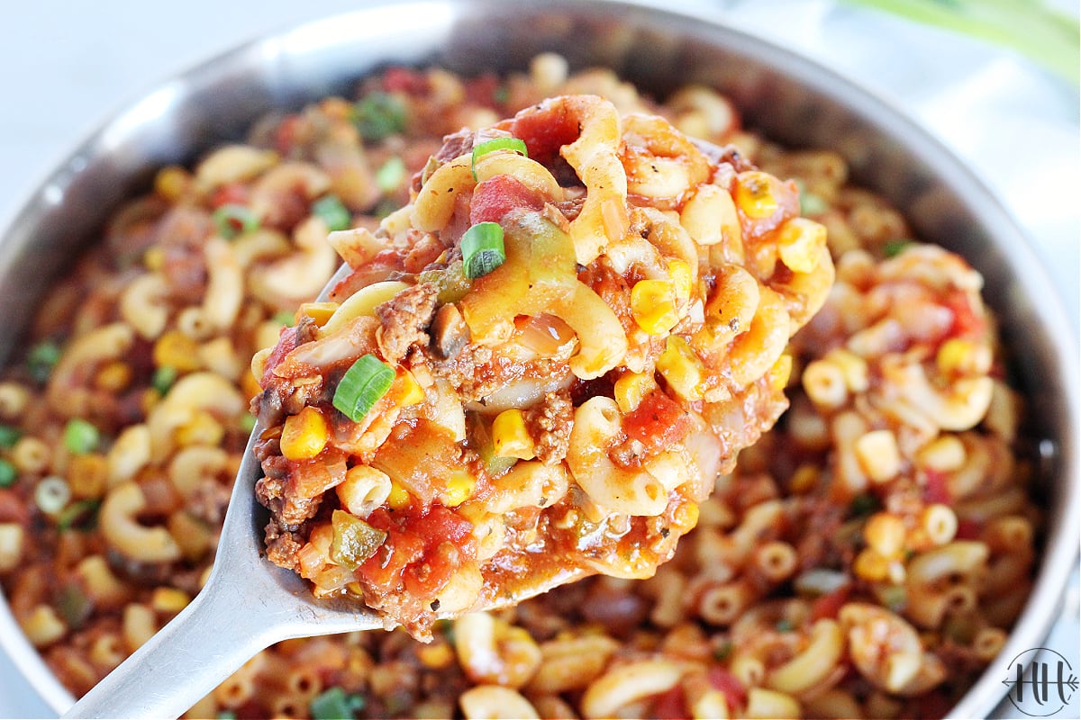 Up close photo of healthy goulash on a large spoon over the pan.