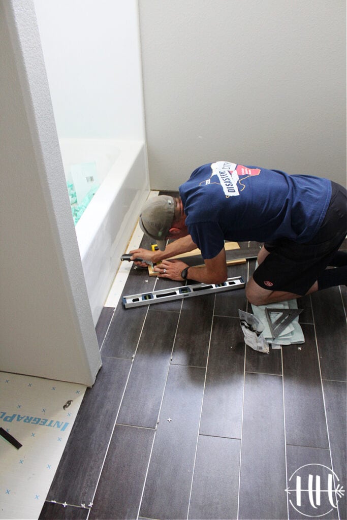 Laying the final pieces of lvt next to a bathtub. 