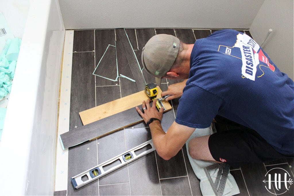 Cutting luxury vinyl tile planks with a knife on a scrap piece of wood. 