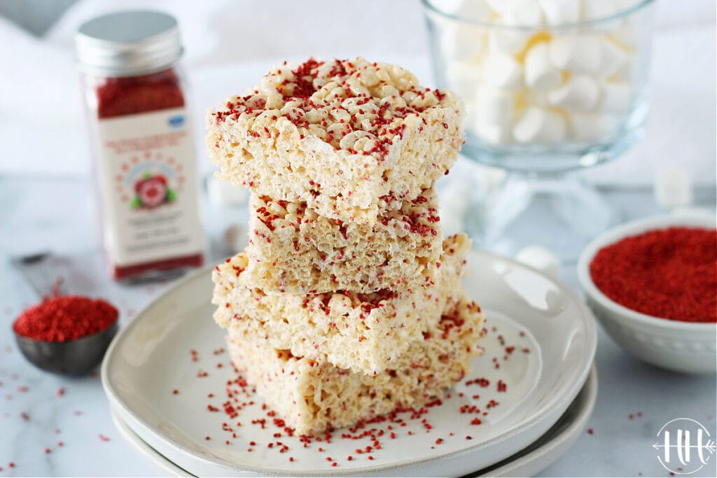 A stack of rice krispies treats with cranberry seeds on a white plate. 