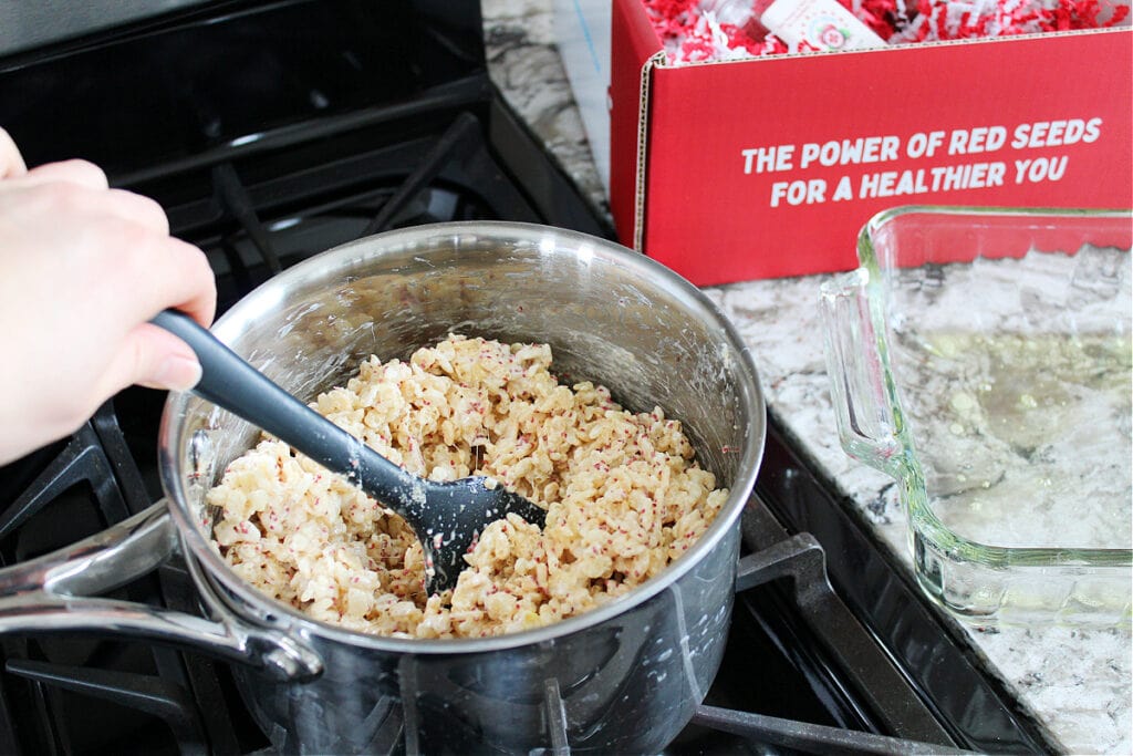 A black spatula stirring together rice crispy treats.